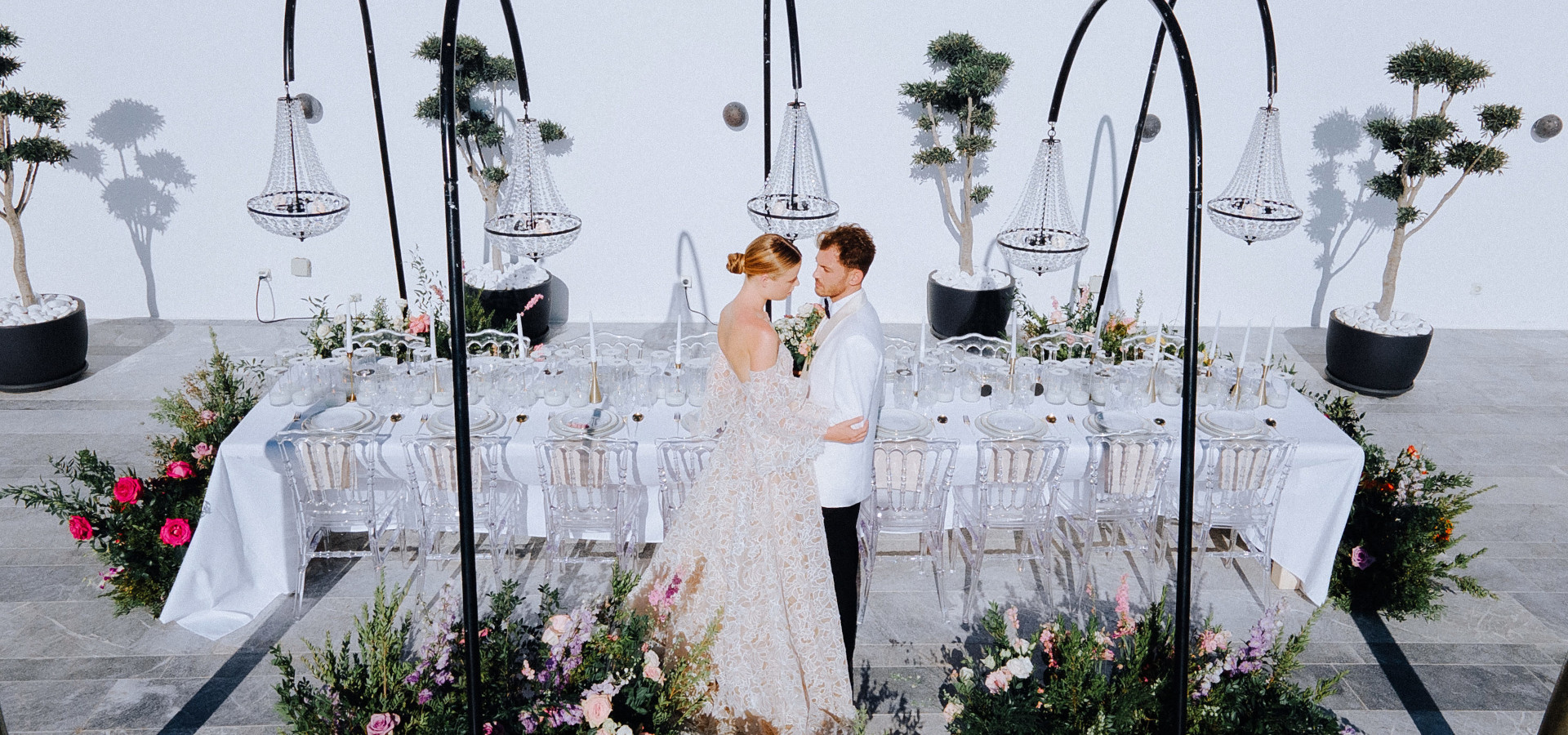 Couple at luxury wedding dinner in Mykonos with crystal chandeliers, elegant tablescape and romantic floral design