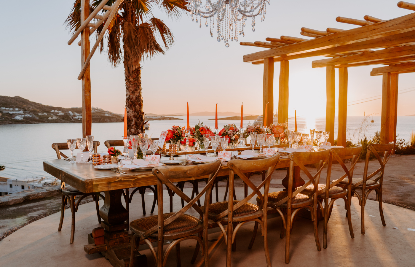 Wedding table set up, with beautiful centerpiece, dinner art a la table, on a Mykonos venue, overlooking the Sunset of The Cycladic island.